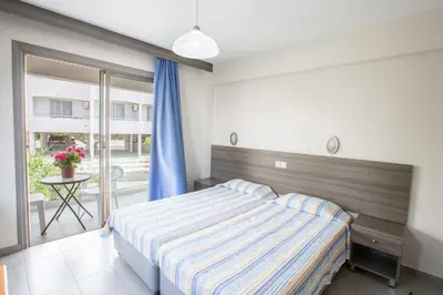 a bedroom with a bed and a balcony with a table at Ayia Napa Holiday Apartment So1 in Ayia Napa