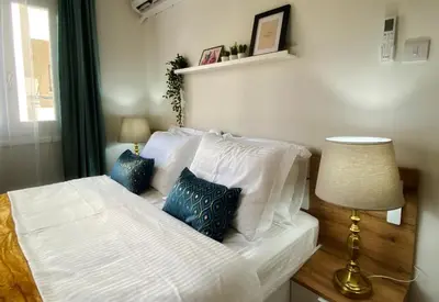 a bedroom with a bed with white sheets and blue pillows at Peaceful 2 bedroom Flat in Engomi