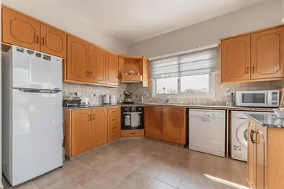 a kitchen with wooden cabinets and white appliances at Villa Mespila_ Ayia Napa in Ayia Napa