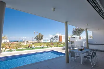 a balcony with a pool and a table and chairs at Protaras Olivine Villa Ol5 in Protaras