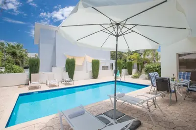 a pool with chairs and an umbrella next to a pool at Protaras Delfini Villa Dv4 in Protaras