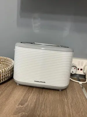 a white toaster sitting on top of a wooden floor at Carisa Holiday rooms in Larnaka