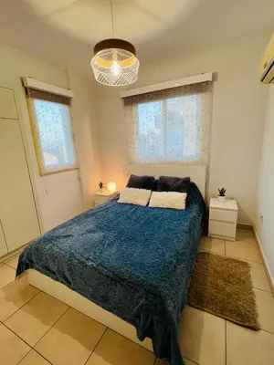 a bedroom with a large bed and two windows at Carisa Holiday rooms in Larnaka