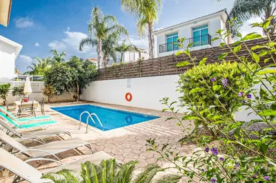 a swimming pool in front of a house with chairs at Villa Delfini 5 in Protaras