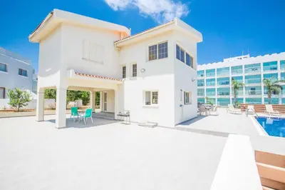 a white house with a pool and a building at Villa Delfini 16 in Protaras