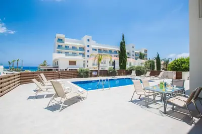 a pool with chairs and a table and a building at Villa Delfini 16 in Protaras