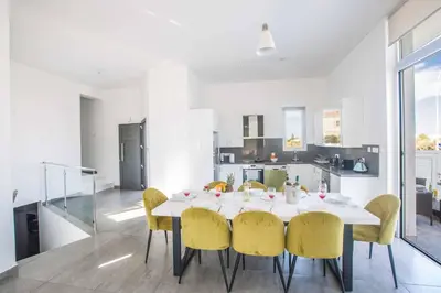 a dining room with a white table and yellow chairs at Villa Polymnia Protaras 1 in Protaras
