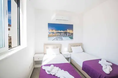 two beds in a small room with a window at Villa Polymnia Protaras 1 in Protaras