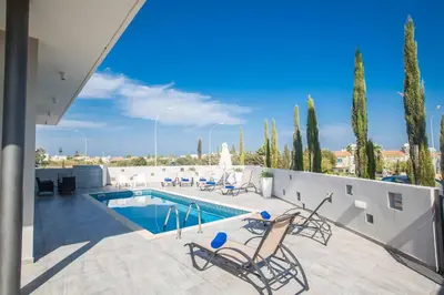 a patio with a swimming pool and two chairs next to a pool at Villa Polymnia Protaras 1 in Protaras