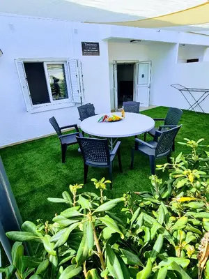 a patio with a table and chairs on the grass at Ayia Anna Apartment in Ayia Napa