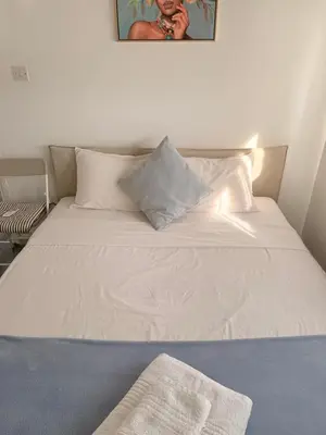 a bed with white sheets and pillows in a room at Zinas modern flat Nicosia in Strovolos