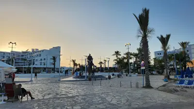 a plaza with a statue and palm trees and buildings at Ayia Napa sea view great location bars & beach in Ayia Napa