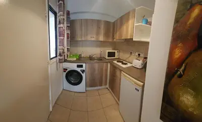 a small kitchen with a washing machine and a sink at Ayia Napa sea view great location bars & beach in Ayia Napa