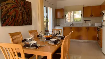 a dining room with a table and chairs and a kitchen at Sunset Sea View Villa in Ayia Napa