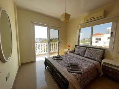 a bedroom with a large bed and a large window at Sunset Sea View Villa in Ayia Napa