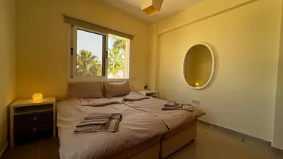 a bedroom with a bed with a mirror and a window at Sunset Sea View Villa in Ayia Napa