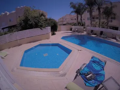 a swimming pool with a chair next to a swimming pool at Andros Apt 2 Bed, Free Wi-fi, Safe, Complex Pool in Paralimni
