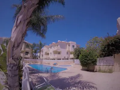 a swimming pool in front of a house with a palm tree at Andros Apt 2 Bed, Free Wi-fi, Safe, Complex Pool in Paralimni