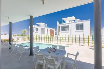 a patio with a table and chairs next to a pool at Protaras Olivine Villa Ol9 in Protaras