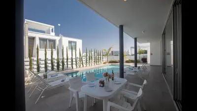 a white table and chairs next to a swimming pool at Protaras Olivine Villa Ol10 in Protaras