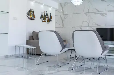 two white chairs in a living room with a couch at Protaras Sunrise Beach Villa 2 in Protaras