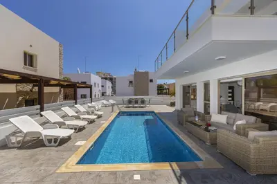 a swimming pool with lounge chairs and a house at Protaras Sunrise Beach Villa 2 in Protaras