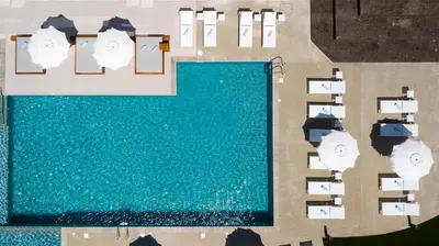 an overhead view of a pool with chairs and umbrellas at The Quality Lodge - Self Check-in in Voroklini