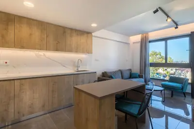 a kitchen with wooden cabinets and a table and chairs at The Quality Lodge - Self Check-in in Voroklini