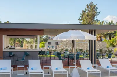 a patio with white chairs and an umbrella at The Quality Lodge - Self Check-in in Voroklini