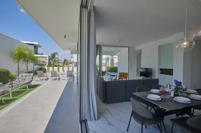 a living room with a dining table and a patio at Protaras Olivine Villa Ol13 in Protaras