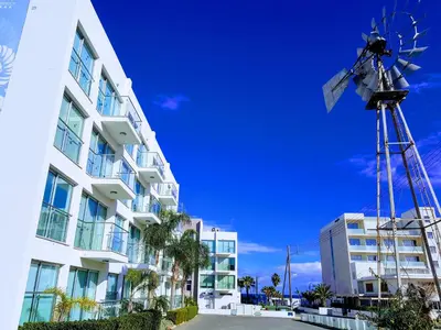 a windmill next to a building and a building with a wind sock at Coralli Spa Resort Protaras Stylish 1 Bedroom apartment in Protaras