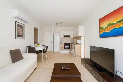 a living room with a white couch and a flat screen tv at Coralli Spa Resort Protaras Stylish 1 Bedroom apartment in Protaras