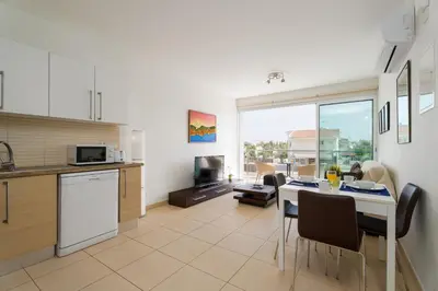 a kitchen and living room with a table and chairs at Coralli Spa Resort Protaras Stylish 1 Bedroom apartment in Protaras