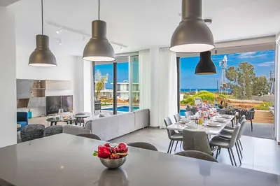 a dining room with tables and chairs and windows at Villa Olivine Pearl 6 in Protaras