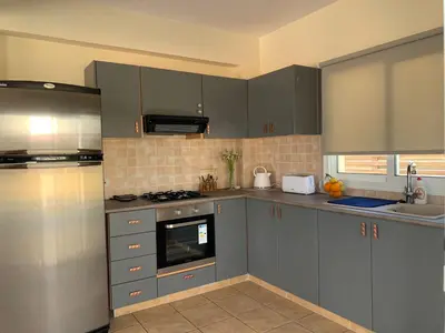a kitchen with gray cabinets and a stove top oven at Moonlight Sea View Villa in Ayia Napa