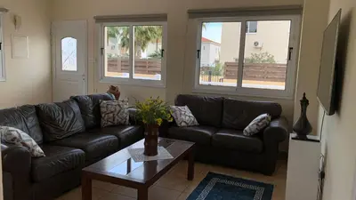 a living room with couches and a table and windows at Moonlight Sea View Villa in Ayia Napa