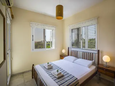 a bedroom with a large bed with two windows at Protaras Villa Amber By The Sea in Protaras