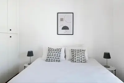 a white bedroom with a white bed with pillows at Urban Condo Promitheos in Nicosia