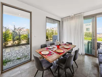 a dining room with a table and chairs and large windows at Azure Villas by Marc in Protaras