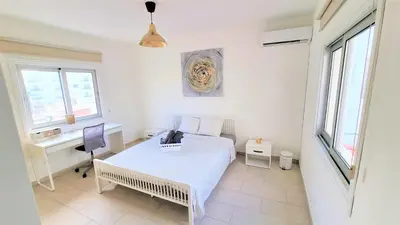 a bedroom with a bed and a desk and windows at Coastal Getaway: 2 Apartments for up to 14 guests! Light-flooded and Spacious in Larnaka
