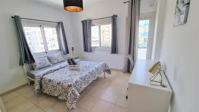 a living room with a table and two windows at Coastal Getaway: 2 Apartments for up to 14 guests! Light-flooded and Spacious in Larnaka