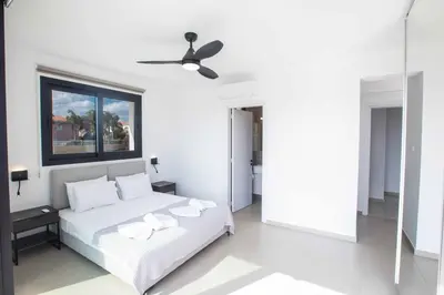 a white bedroom with a bed and a ceiling fan at Protaras Holiday Villa TI39 in Paralimni