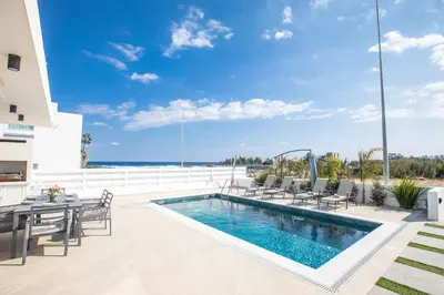 a patio with a pool and chairs and a table at Protaras Holiday Villa TI39 in Paralimni