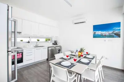 a white kitchen with a table and white chairs at Protaras Greco Villa CCV5 in Protaras