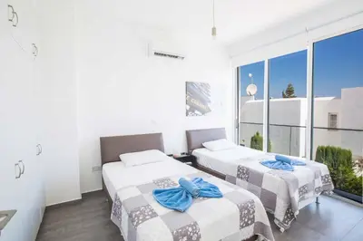 two beds in a room with a large window at Protaras Greco Villa CCV5 in Protaras
