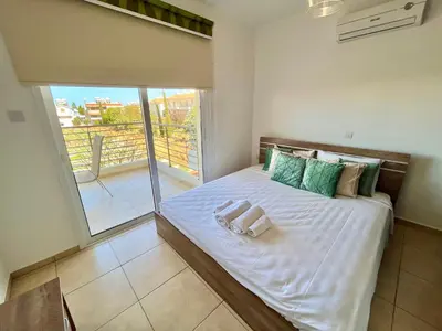 a bedroom with a large bed with a balcony at Mythical Sands Holiday Apartment in Paralimni