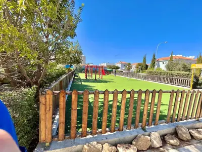 a wooden fence with a playground in a park at Mythical Sands Holiday Apartment in Paralimni