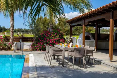 a table and chairs next to a swimming pool at Cape Greco Palm Trees Villa in Ayia Napa