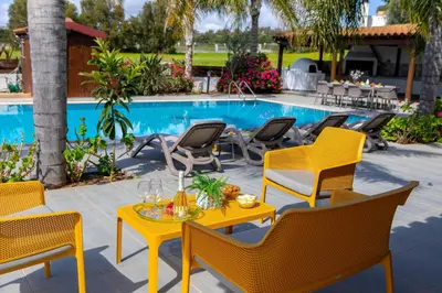 a patio with chairs and a table and a pool at Cape Greco Palm Trees Villa in Ayia Napa
