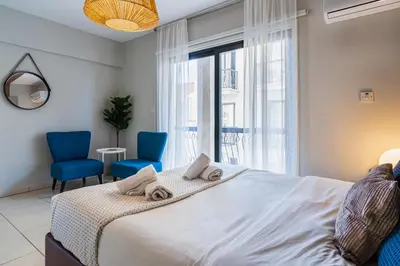 a bedroom with a bed and two blue chairs at Gitane 1-Bedroom Apartment in Larnaca in Larnaka